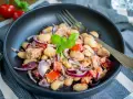 Herzhafter Thunfischsalat mit weißen Bohnen, Tomaten und roten Zwiebeln, garniert mit Basilikum. Ein köstlicher und einfacher Salat.