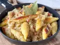 Schupfnudeln mit Sauerkraut, Speck und Lorbeerblättern in einer Pfanne. Ein herzhaftes Gericht, das zum Genießen einlädt.