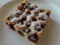 Zwei Stücke Kirschstreuselkuchen vom Blech, mit Puderzucker bestäubt, auf einem weißen Teller.