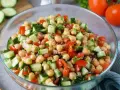 Frischer Kichererbsen Salat mit Gurken, Tomaten und Kräutern in einer Glasschüssel. Ein leichter und gesunder Genuss.
