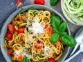 Herzhafte Zucchini-Nudeln mit Tomaten und Basilikum, bestreut mit Parmesan. Ein leichter Genuss!