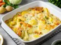 Ein köstlicher vegetarischer Auflauf mit Kartoffeln, Karotten und Erbsen, überbacken mit Käse und garniert mit Petersilie.