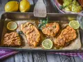 Saftiges Schnitzel im Backofen, goldbraun paniert, mit frischer Petersilie und Zitronenspalten garniert. Ein Genuss!