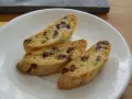 Drei knusprige Cantuccini mit Schokolade liegen auf einem weißen Teller.