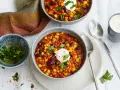 Herzhaftes Chili sin Carne mit Mais, Bohnen und Linsen, garniert mit einem Klecks Sauerrahm und frischer Petersilie.