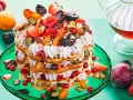 Eine mehrstöckige Waffeltorte mit Mascarpone-Creme, Beeren, Pfirsichen und Nüssen, garniert mit frischen Früchten.
