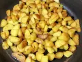 Goldbraune bratkartoffeln aus gekochten kartoffeln brutzeln in der Pfanne. Sie sind knusprig und duften herrlich.