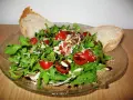 Frischer Rucola Salat mit Kirschtomaten, Pinienkernen und Parmesan, beträufelt mit Balsamico-Dressing. Dazu knuspriges Brot.