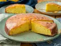 Ein saftiger Zitronenkuchen mit glänzender Glasur, auf einem grünen Teller serviert. Ein Stück wird gerade herausgehoben.