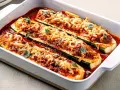Herzhafte Zucchini-Schiffchen, gefüllt mit Hackfleisch und Tomatensauce, überbacken mit geschmolzenem Käse und garniert mit frischen Kräutern.