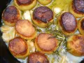 Goldbraun gebratene Fondant-Kartoffeln mit Rosmarin und Knoblauch in einer Pfanne.