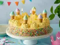 Bunte Torte mit Streuseln und Eiswaffel-Deko, perfekt für kinder torten rezepte einfach. Kerzen brennen, eine märchenhafte Feier beginnt.