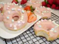 Leckere Donuts mit rosa Glasur und Marshmallows, perfekt für ein schnelles Donuts Rezept aus dem Backofen. Frische Erdbeeren garnieren das süße Gebäck.