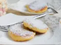 Zwei goldbraune Quarkkeulchen, bestäubt mit Puderzucker, liegen auf einem Teller. Ein einfaches Quarkkeulchen Rezept für süße Momente.