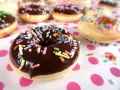 Bunte Streusel auf Schokoladen- und Zuckerguss-Donuts, die an ein leckeres Donut Teig Rezept erinnern.