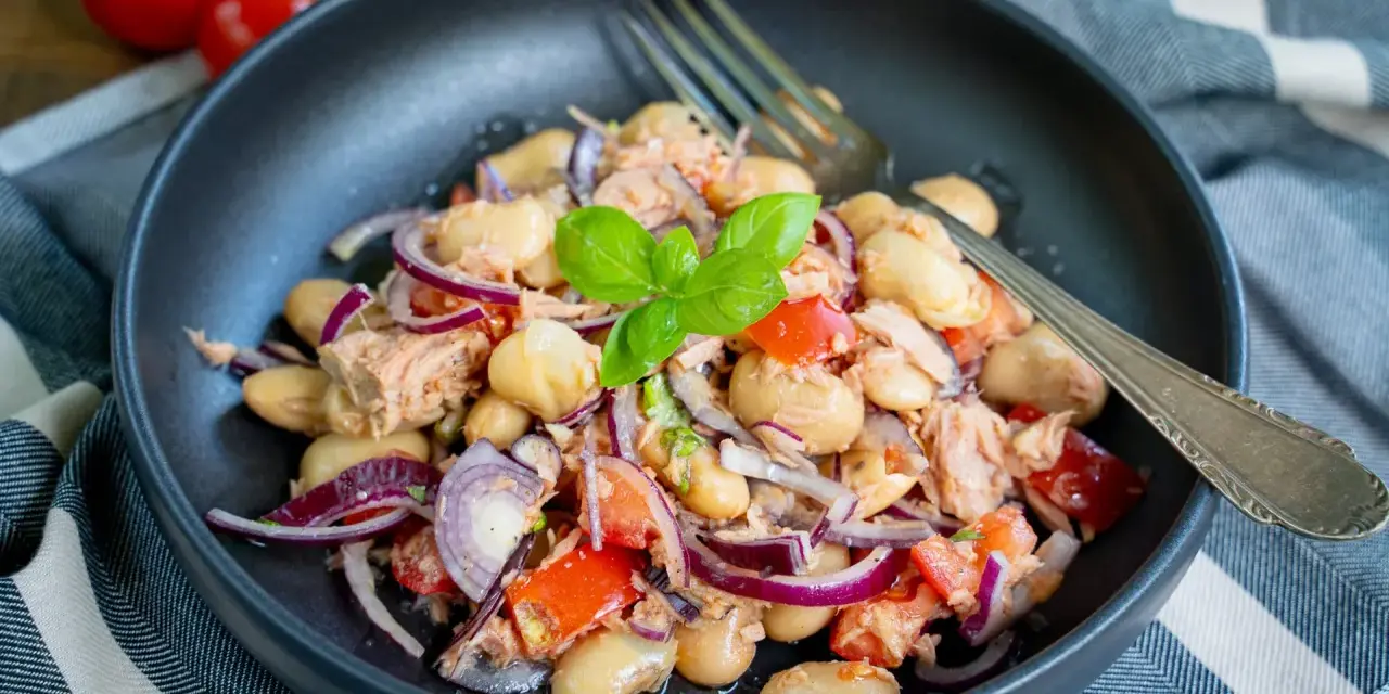 Herzhafter Thunfischsalat mit weißen Bohnen, Tomaten und roten Zwiebeln, garniert mit Basilikum. Ein köstlicher und einfacher Salat.