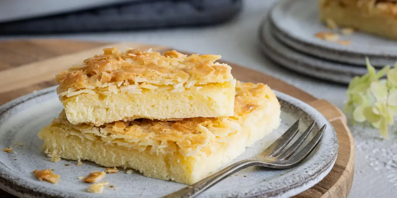 Zwei Stücke saftiger Butterkuchen mit knuspriger Mandelkruste auf einem Teller, bereit zum Genießen. Ein köstliches butterkuchen rezept.