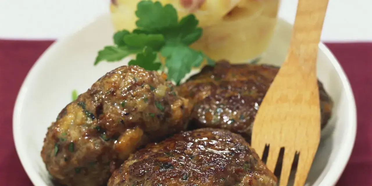 Saftige Frikadellen mit cremigem Kartoffelsalat, garniert mit Petersilie. Ein klassisches Gericht, das immer schmeckt.
