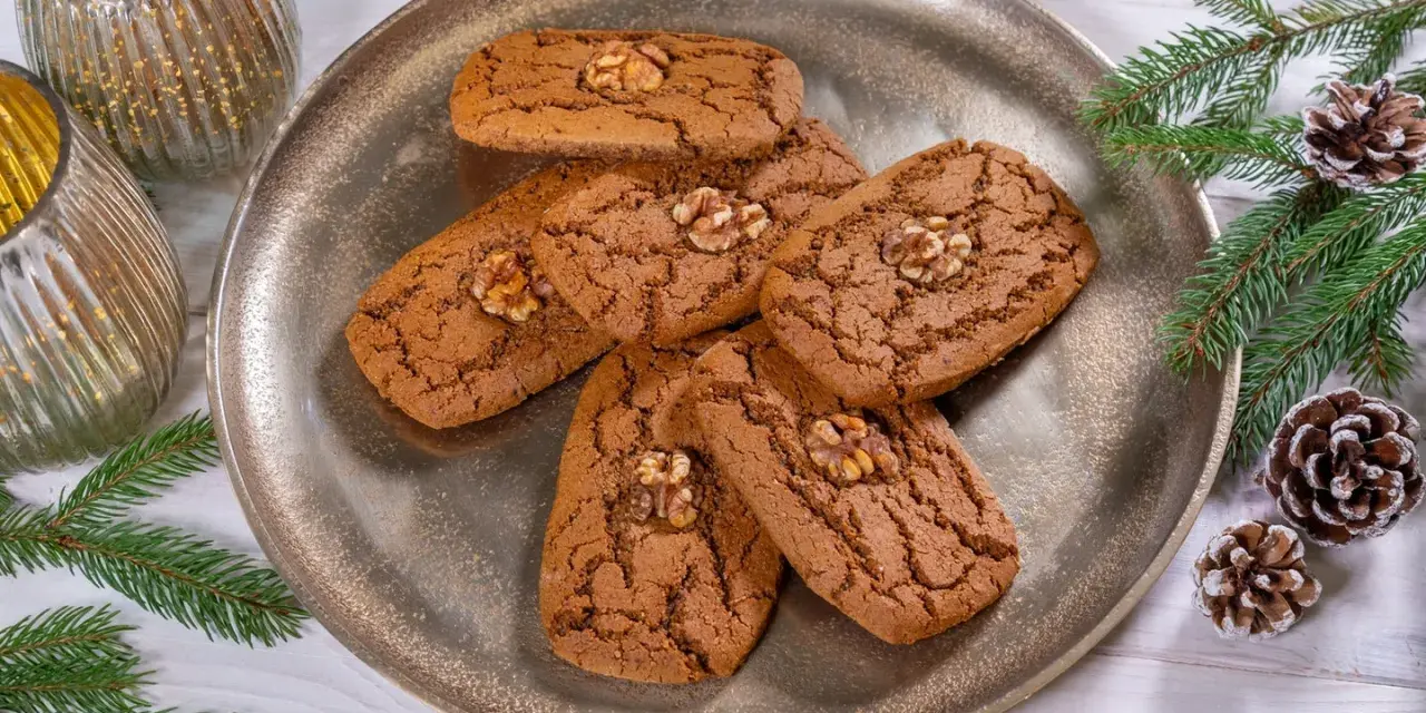 Aachener Printen Rezept: Köstliche, nussgekrönte Printen auf einem silbernen Teller, umgeben von Tannenzweigen und Zapfen. Perfekt für die Weihnachtszeit.
