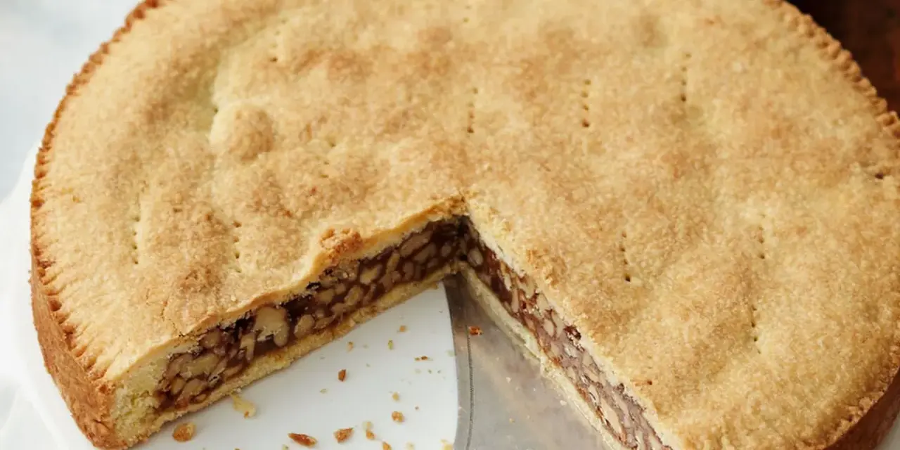 Eine köstliche Engadiner Nusstorte mit goldbraunem Teig und einer reichhaltigen Nussfüllung, gerade angeschnitten.