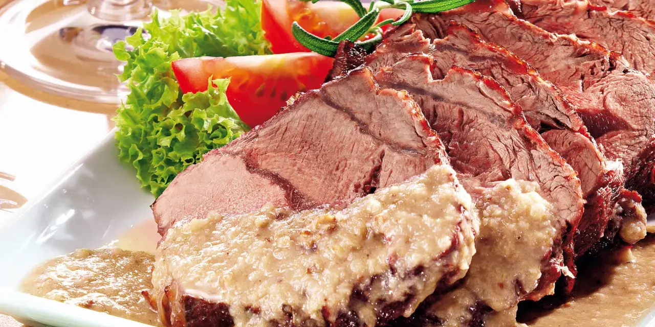 Saftiger Sauerbraten, perfekt für Ihr nächstes Sauerbraten Rezept, serviert mit frischem Salat und Tomaten.