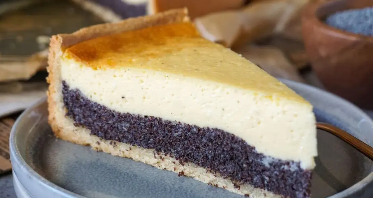 Ein Stück Mohnkuchen mit cremigem Käse-Topping und Mohnback-Schicht auf einem grauen Teller.