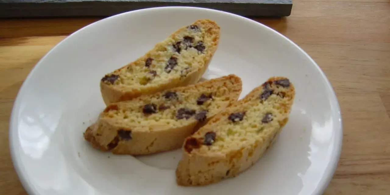 Drei knusprige Cantuccini mit Schokolade liegen auf einem weißen Teller.
