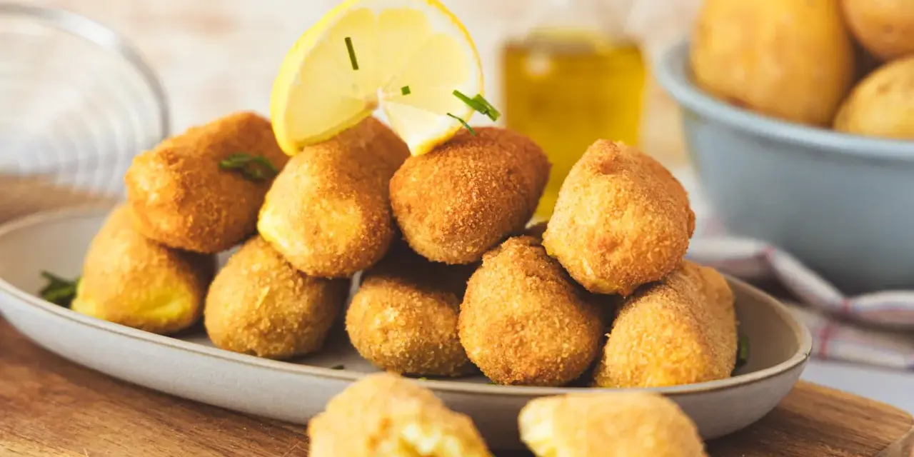 Goldbraune, knusprige Kroketten, frisch zubereitet, mit Zitrone und Kräutern garniert. Perfekt zum Selbermachen!