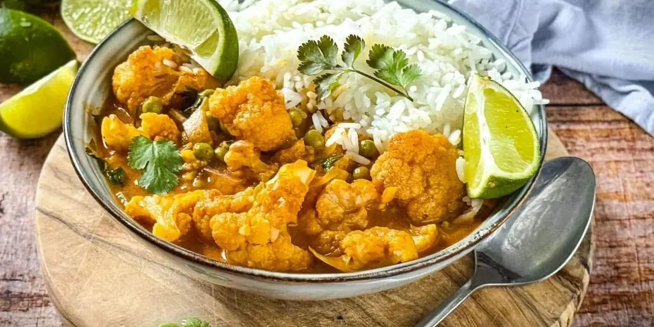 Herzhaftes Curry mit Blumenkohl und Reis, garniert mit Limettenspalten. Ein köstliches Beispiel für Blumenkohl Rezepte.
