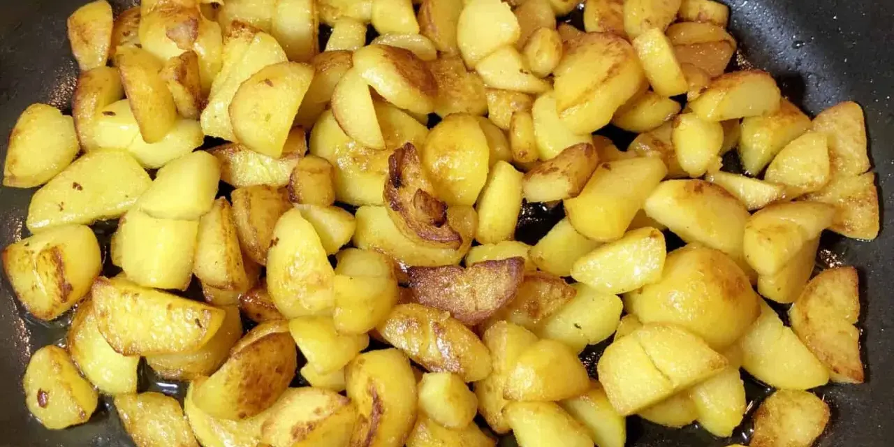 Goldbraune bratkartoffeln aus gekochten kartoffeln brutzeln in der Pfanne. Sie sind knusprig und duften herrlich.