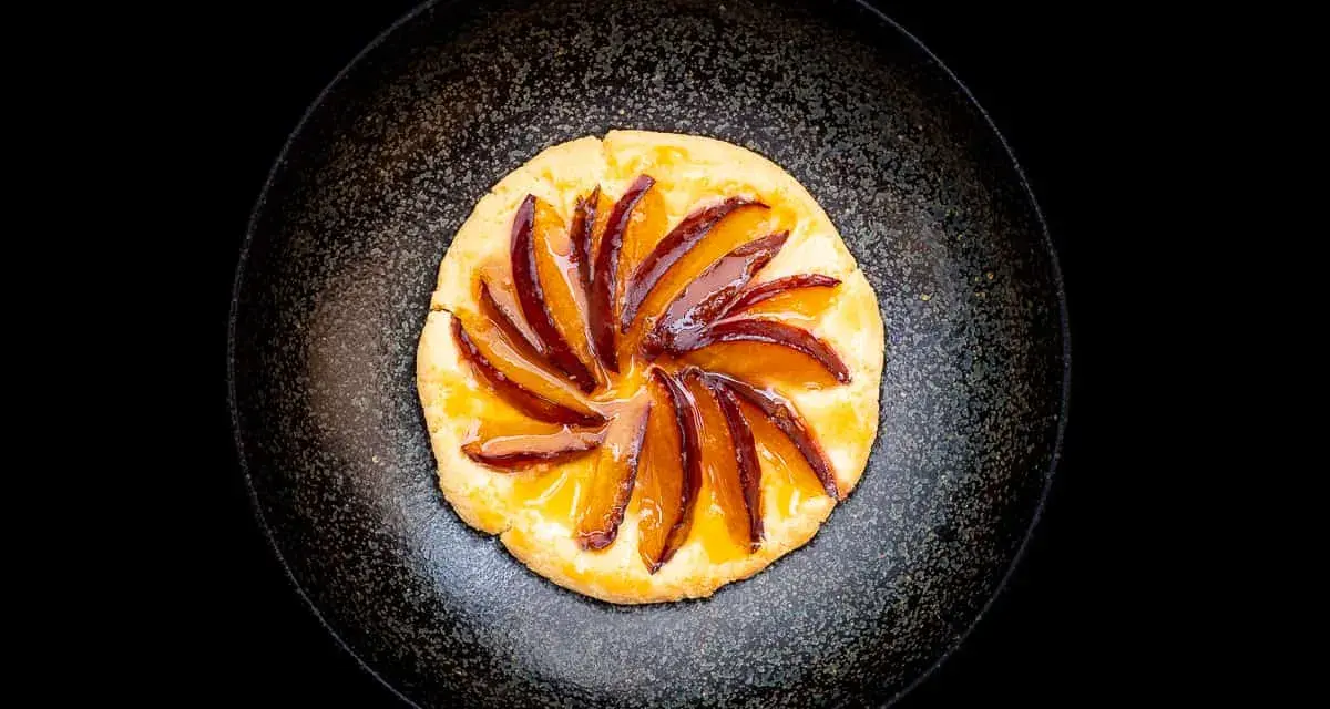 Eine köstliche Zwetschgen Tarte, mit saftigen Zwetschgenspalten, kunstvoll auf einem knusprigen Teig arrangiert und mit glänzendem Sirup überzogen.