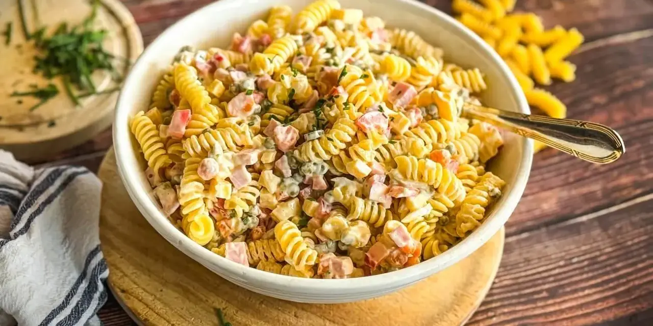 Ein cremiger, sommerlicher Nudelsalat mit Spiralnudeln, Schinkenwürfeln und Erbsen, garniert mit frischen Kräutern. Perfekt für warme Tage!
