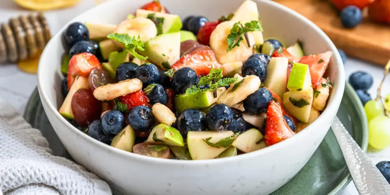 Ein bunter Obstsalat mit Erdbeeren, Blaubeeren, Bananen und Äpfeln, perfekt für ein leichtes obstsalat rezept.