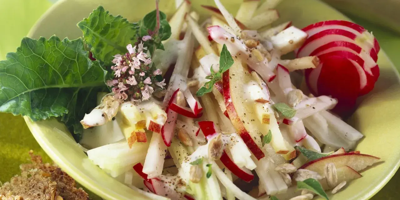 Frischer Kohlrabi Salat mit Apfel, Radieschen und Kräutern, garniert mit Sonnenblumenkernen. Ein leichter Genuss!