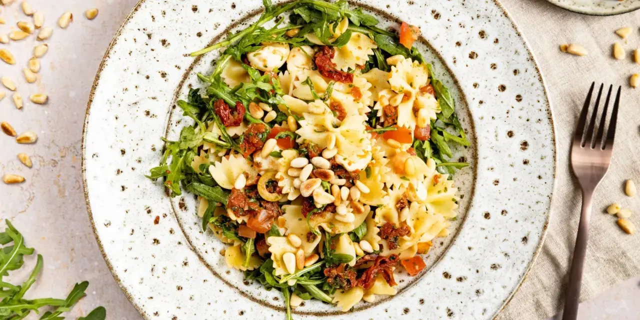Mediterraner Salat mit Farfalle, getrockneten Tomaten, Rucola und Pinienkernen. Ein leichter Genuss!