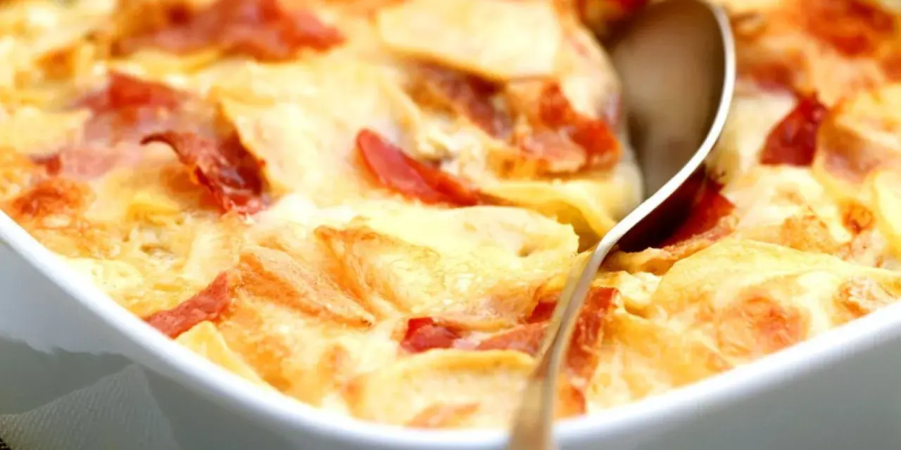 Schinken Sahne Auflauf ohne Vorkochen: Kartoffelscheiben mit Schinken und cremiger Sauce im Auflauf, bereit zum Servieren.