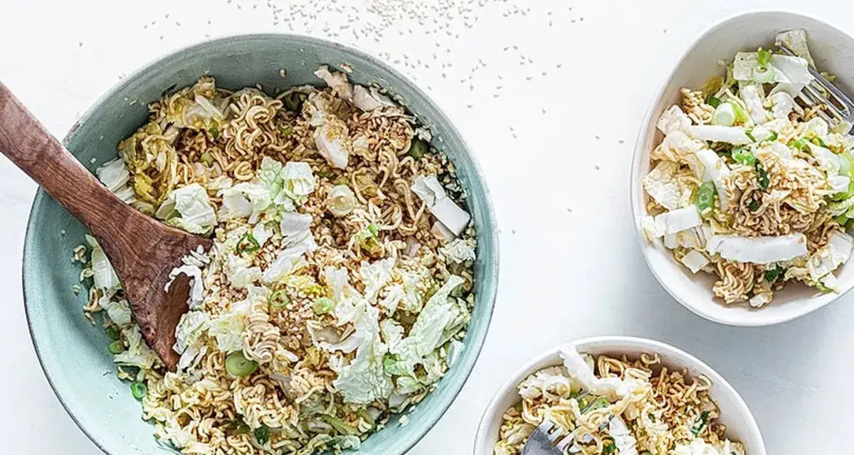 Ein großer Schüssel mit "friss dich dumm salat" aus Nudeln, Chinakohl und Frühlingszwiebeln, daneben zwei kleinere Schüsseln.