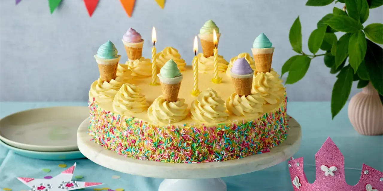 Bunte Torte mit Streuseln und Eiswaffel-Deko, perfekt für kinder torten rezepte einfach. Kerzen brennen, eine märchenhafte Feier beginnt.