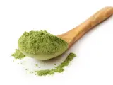 Ein Holzlöffel voller feinem, grünem Pulver, ideal für Schabzigerklee Rezepte.