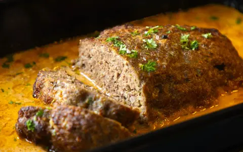 Saftiger Hackbraten mit cremiger Sauce, garniert mit Petersilie. Ein köstliches Hackbraten Rezept, das jeden begeistert.