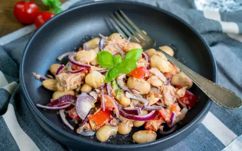 Herzhafter Thunfischsalat mit weißen Bohnen, Tomaten und roten Zwiebeln, garniert mit Basilikum. Ein köstlicher und einfacher Salat.