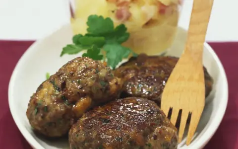 Saftige Frikadellen mit cremigem Kartoffelsalat, garniert mit Petersilie. Ein klassisches Gericht, das immer schmeckt.