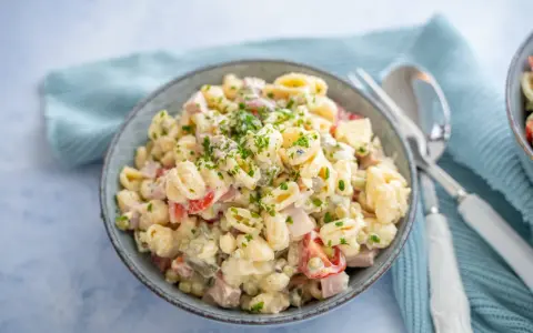 Schüssel mit cremigem Nudelsalat, garniert mit Petersilie. Das cremige nudelsalat dressing macht ihn unwiderstehlich.