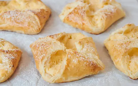 Goldbraune Quarktaschen, mit Puderzucker bestäubt, sehen aus wie ein köstliches Quarktaschen Rezept.