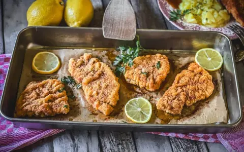 Saftiges Schnitzel im Backofen, goldbraun paniert, mit frischer Petersilie und Zitronenspalten garniert. Ein Genuss!