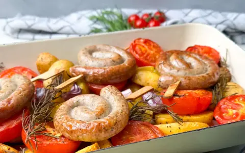 Bratwurst-Ringe mit Kartoffeln, Tomaten und Rosmarin im Ofen gebacken.