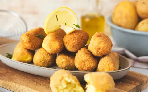 Goldbraune, knusprige Kroketten, frisch zubereitet, mit Zitrone und Kräutern garniert. Perfekt zum Selbermachen!