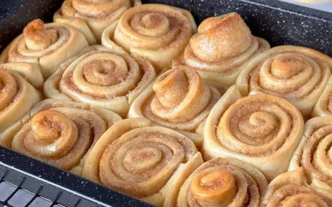 Frisch gebackene Zimtschnecken in einer Backform, goldbraun und duftend.