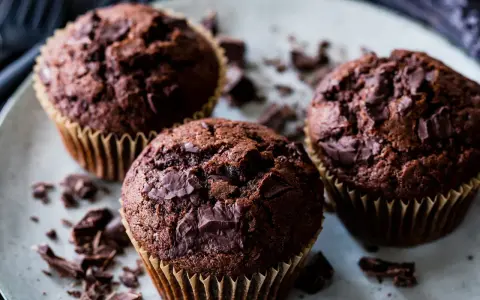 Drei saftige Schokomuffins mit Schokoladenstückchen, perfekt für ein schnelles schokomuffins rezept.