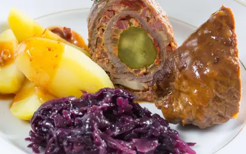 Rinderrouladen mit Rotkohl und Kartoffeln, ein deftiges Gericht, das nach Hausmannskost schmeckt.